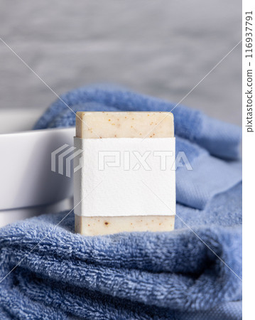 Soap bar with blank label on blue towels near vessel sink in bathroom closeup, mockup 116937791