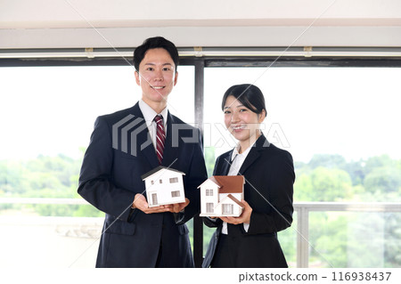 Asian male and female office workers holding house model Asian male and female office workers holding house model 116938437