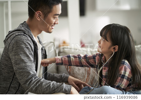 asian father and daughter playing doctor and patient game at home asian father and daughter playing doctor and patient game at home 116939086