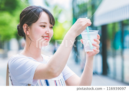 Young woman drinking water outdoors 116939097