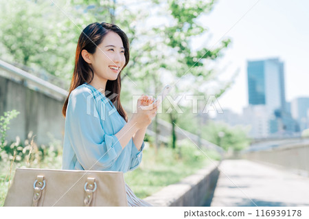 A woman looking at a smartphone outdoors A woman looking at a smartphone outdoors 116939178