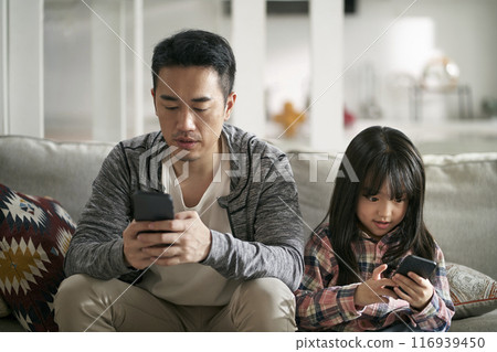asian father and daughter using mobile phone together at home asian father and daughter using mobile phone together at home 116939450