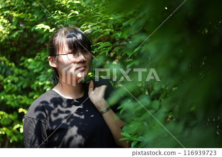 Portrait of the Asian glassese Thai woman is standing in the garden in the morning. Portrait of the Asian glassese Thai woman is standing in the garden in the morning. 116939723