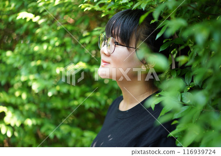 Portrait of the Asian glassese Thai woman is standing in the garden in the morning. 116939724