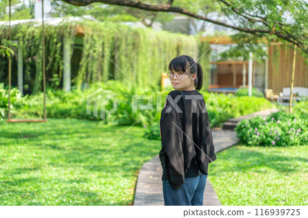 Portrait of the Asian glassese Thai woman is standing in the garden in the morning. 116939725