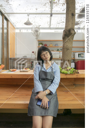 Asian glasses Woman thinks for lunch menu in front of wooden counter kitchen. Thailand style. 116939738