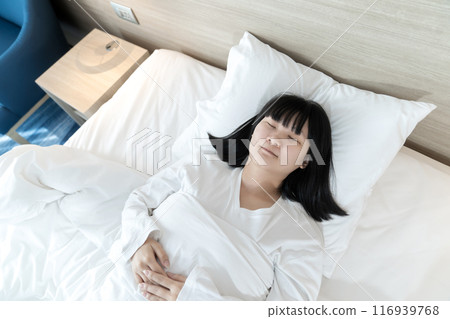 Asian woman sleeps on white bed after exhausted and tried all day. 116939768