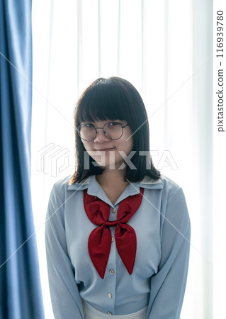Asian glasses cute woman in blue shirt beside the curtain and window light in bedroom. Asian glasses cute woman in blue shirt beside the curtain and window light in bedroom. 116939780