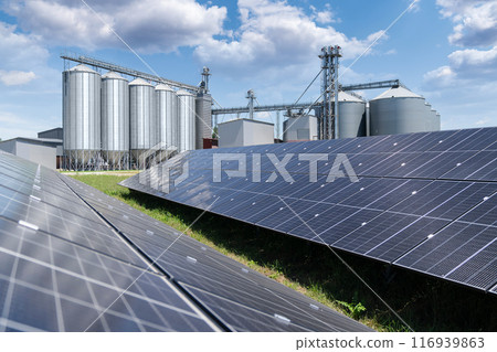 Modern farm using renewable energy. Solar panels with silos in the background. 116939863