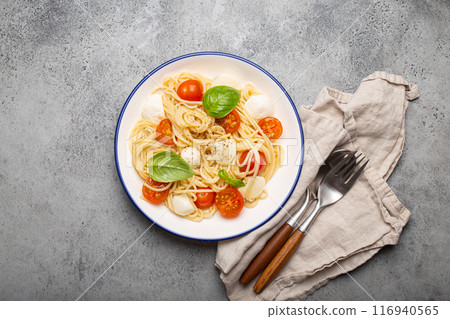 Spaghetti with cherry tomatoes and mozzarella being served on a plate 116940565