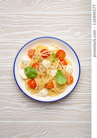 Plate of spaghetti pasta with cherry tomatoes and mozzarella cheese on white background Plate of spaghetti pasta with cherry tomatoes and mozzarella cheese on white background 116940577