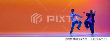 Dynamic image of talented young man and woman, dancers performing hip-hop against gradient studio background in neon light Dynamic image of talented young man and woman, dancers performing hip-hop against gradient studio background in neon light 116942465