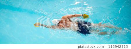 Banner. Swimmer with yellow paddle glides through pool, honing his freestyle technique under sun outdoor. 116942513