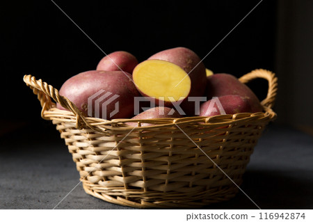 Beautiful pink new potatoes in a wicker basket, low angle 116942874