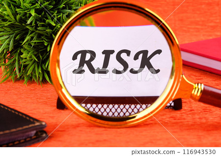 Risk management concept. RISK word through a magnifying glass on a white business card on an orange background 116943530