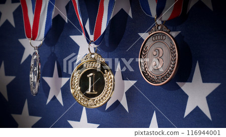 Gold silver and bronze mockup trophy medals with ribbon against United States of America flag. Represent winner of national or international olympic sport competition. Award winner and victory concept Gold silver and bronze mockup trophy medals with ribbon against United States of America flag. Represent winner of national or international olympic sport competition. Award winner and victory concept 116944001