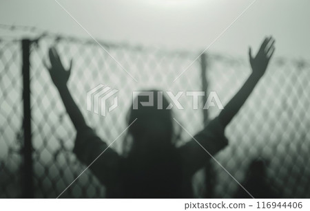 Hand Reaching Through Barbed Wire Fence 116944406