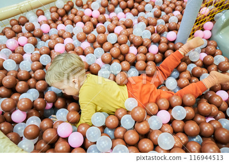 An unrecognizable boy lies on plastic balls in a large dry children's pool in the play center. Have fun in the game room. Active leisure. With space to copy. High quality photo An unrecognizable boy lies on plastic balls in a large dry children's pool in the play center. Have fun in the game room. Active leisure. With space to copy. High quality photo 116944513