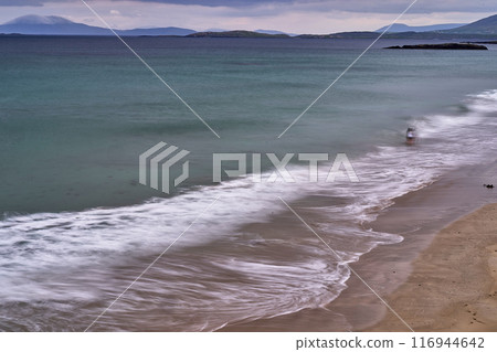 long exposure beach waves around rock cloudy day 116944642