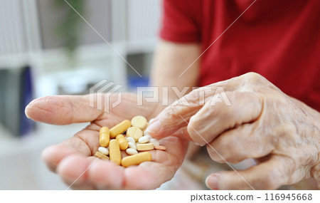 Elderly Woman Counts Pills And Capsules In Her Palm 116945668