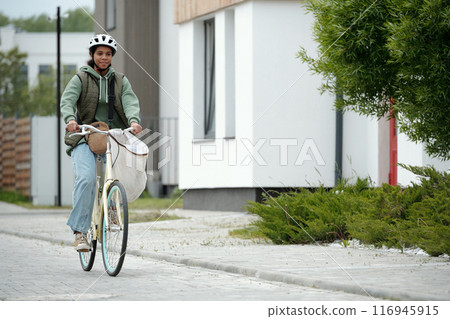 Teenager riding post bicycle along road 116945915