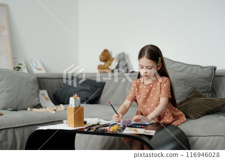 Serious little girl drawing with crayons Serious little girl drawing with crayons 116946028