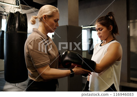 Helping put on leather boxing gloves Helping put on leather boxing gloves 116946083