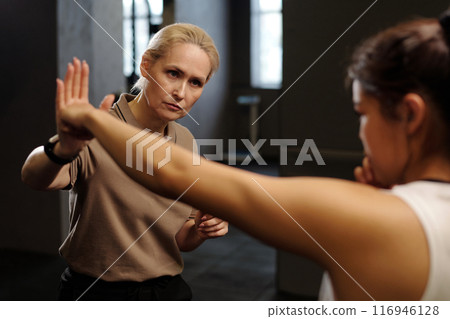 Mature boxing trainer looking at learner 116946128