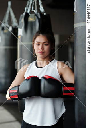 Confident young woman in boxing gloves 116946187