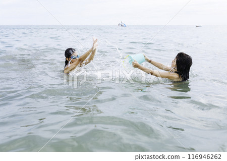 two playing playing with water standing in the sea 116946262