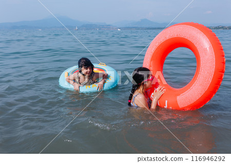 two girls having fun in the lake with inflatable rings 116946292