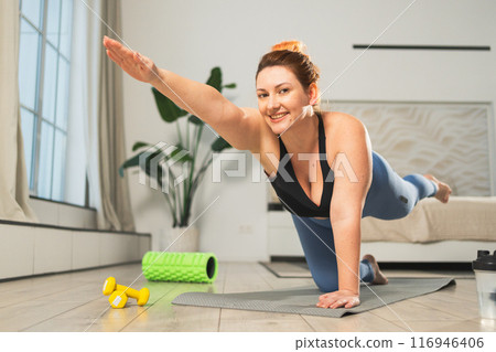 Yoga fitness workout training. Woman practicing yoga at home. Plus size female doing sports exercise on yoga mat indoor. Girl in sportswear have training workout for weight loss. Sport and fitness Yoga fitness workout training. Woman practicing yoga at home. Plus size female doing sports exercise on yoga mat indoor. Girl in sportswear have training workout for weight loss. Sport and fitness 116946406