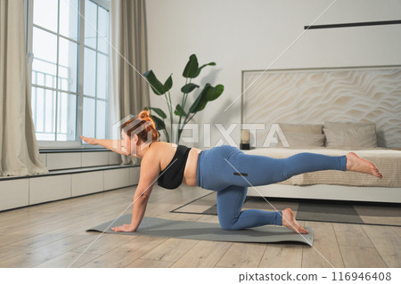Yoga fitness workout training. Woman practicing yoga at home. Plus size female doing sports exercise on yoga mat indoor. Girl in sportswear have training workout for weight loss. Sport and fitness Yoga fitness workout training. Woman practicing yoga at home. Plus size female doing sports exercise on yoga mat indoor. Girl in sportswear have training workout for weight loss. Sport and fitness 116946408