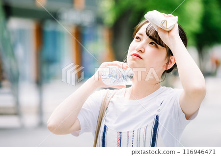 A young woman cools herself down with a plastic bottle during the heatwave 116946471