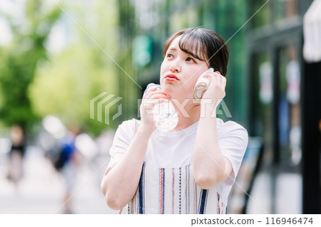 一名年輕女子忍受酷熱,用塑膠瓶為自己降溫 一名年輕女子忍受酷熱,用塑膠瓶為自己降溫 116946474