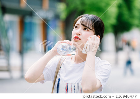 A young woman cools herself down with a plastic bottle during the heatwave A young woman cools herself down with a plastic bottle during the heatwave 116946477