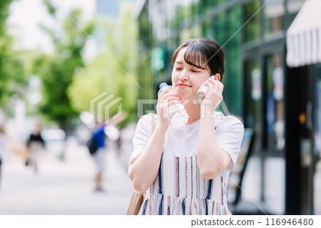 A young woman cools herself down with a plastic bottle during the heatwave A young woman cools herself down with a plastic bottle during the heatwave 116946480