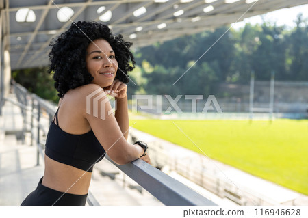 Cute smiling woman in sportswear looking contented Cute smiling woman in sportswear looking contented 116946628
