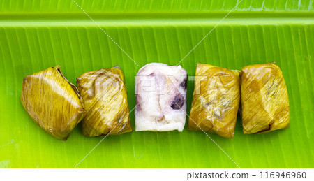 Bundled boiled sticky rice with banana and black beans wrapped in banana leaves 116946960