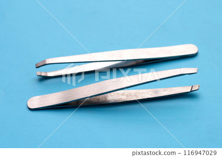 Tweezers on blue background. Copy space 116947029
