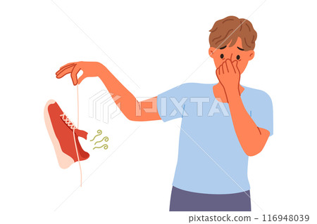 Man suffers from onychomycosis and stinky feet, covers nose with hands and holds stinky shoe 116948039