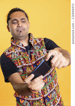 Man entertained by playing videogames on smartphone in landscape mode, enjoying leisure time. Person enjoying games on phone, competing against other players, isolated over studio background Man entertained by playing videogames on smartphone in landscape mode, enjoying leisure time. Person enjoying games on phone, competing against other players, isolated over studio background 116948453