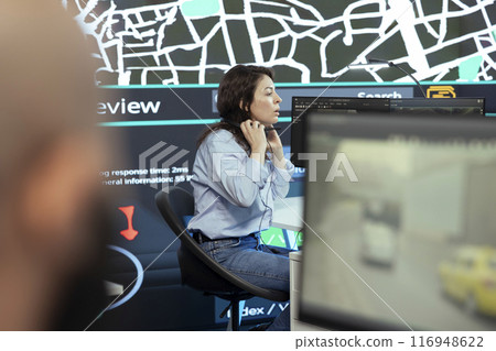 Call center operator puts headphones on to handle order delays complains from customers, working to ensure faster delivery time via satellite map and CCTV system. Cargo tracing. Call center operator puts headphones on to handle order delays complains from customers, working to ensure faster delivery time via satellite map and CCTV system. Cargo tracing. 116948622