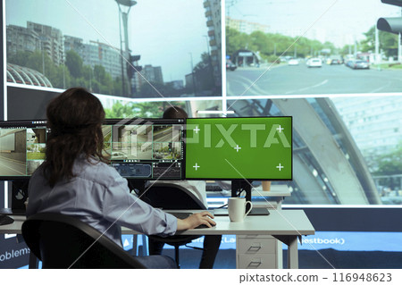 Woman employee monitoring traffic via surveillance radar footage, using a greenscreen in control center. Operator studying CCTV security system around the city streets, gathers cars information. Woman employee monitoring traffic via surveillance radar footage, using a greenscreen in control center. Operator studying CCTV security system around the city streets, gathers cars information. 116948623