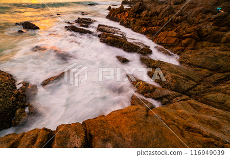 Long exposure image of Dramatic sky seascape with rocks and waves crashing on seashore in sunset or sunrise scenery background 116949039