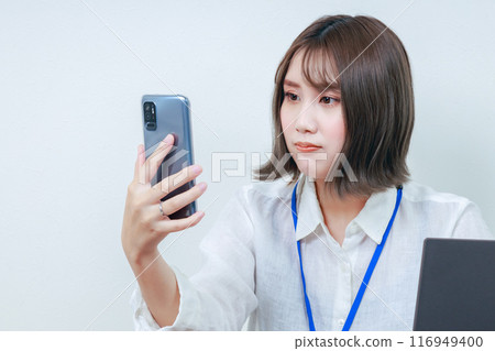 女工作人員一臉酸澀地看著自己的智慧型手機 116949400