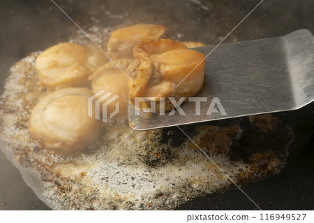 Grilled scallops with butter. Lift the scallops with a spatula. Grilled scallops with butter. Lift the scallops with a spatula. 116949527