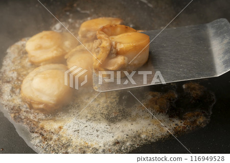 Grilled scallops with butter. Lift the scallops with a spatula. 116949528