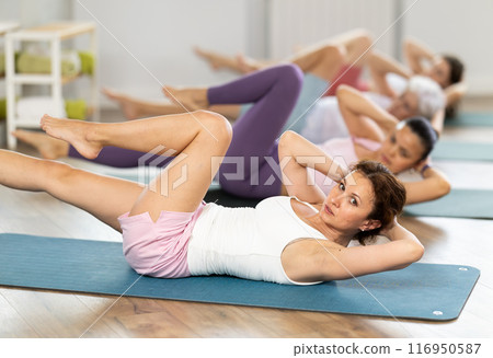 Athletic women doing pilates or aerobics - doing back exercises during group training in gym 116950587