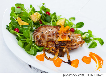 Cooked fried pork meat with herbs, sauce and berries on plate 116950625